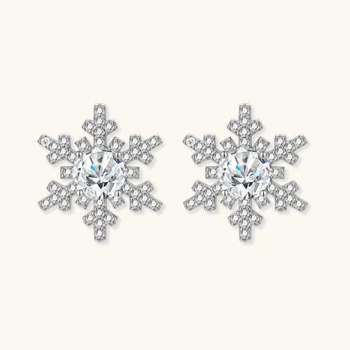 Sterling silver snowflake stud earrings with brilliant moissanite centers and intricate geometric patterns on cream background